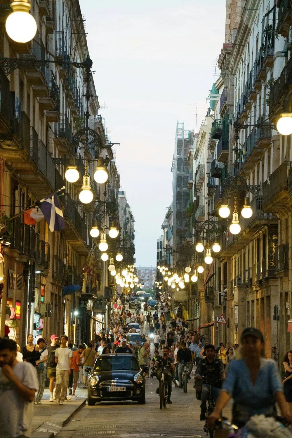 Busy Barcelona old-town street lit by ornate lamps at dusk